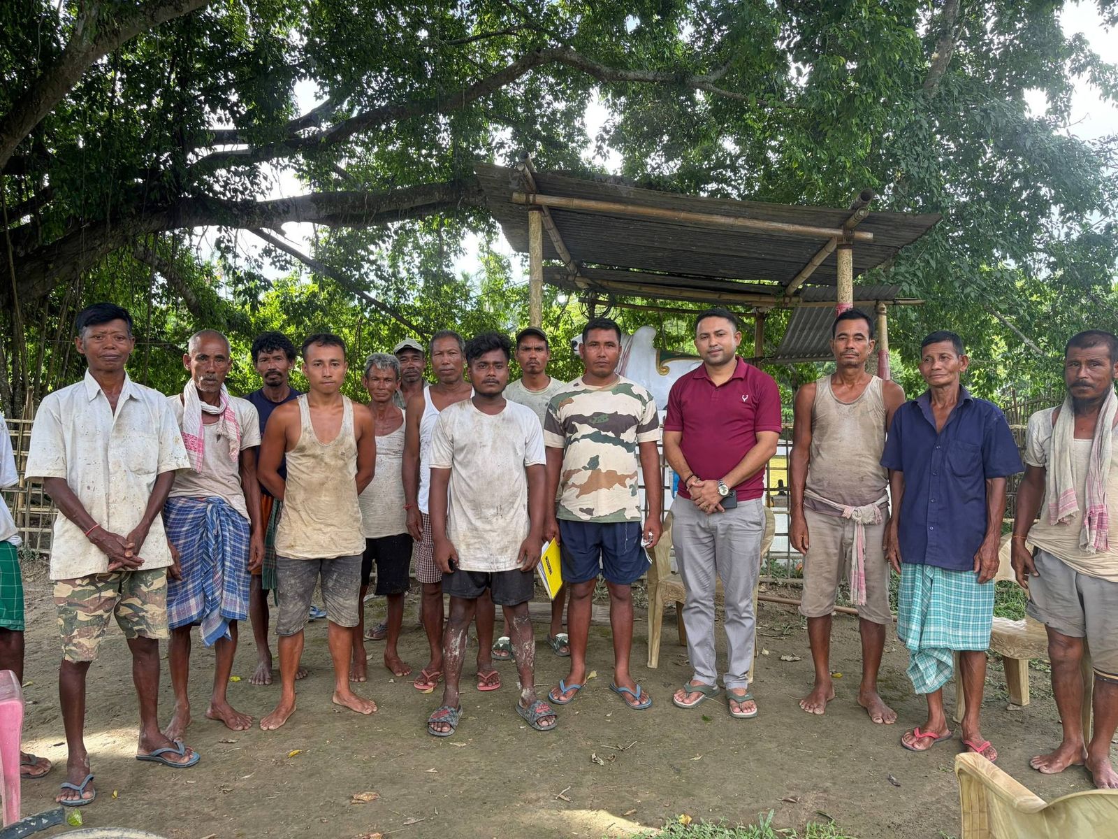 Rural men standing with a PSF team member under trees after a field visit